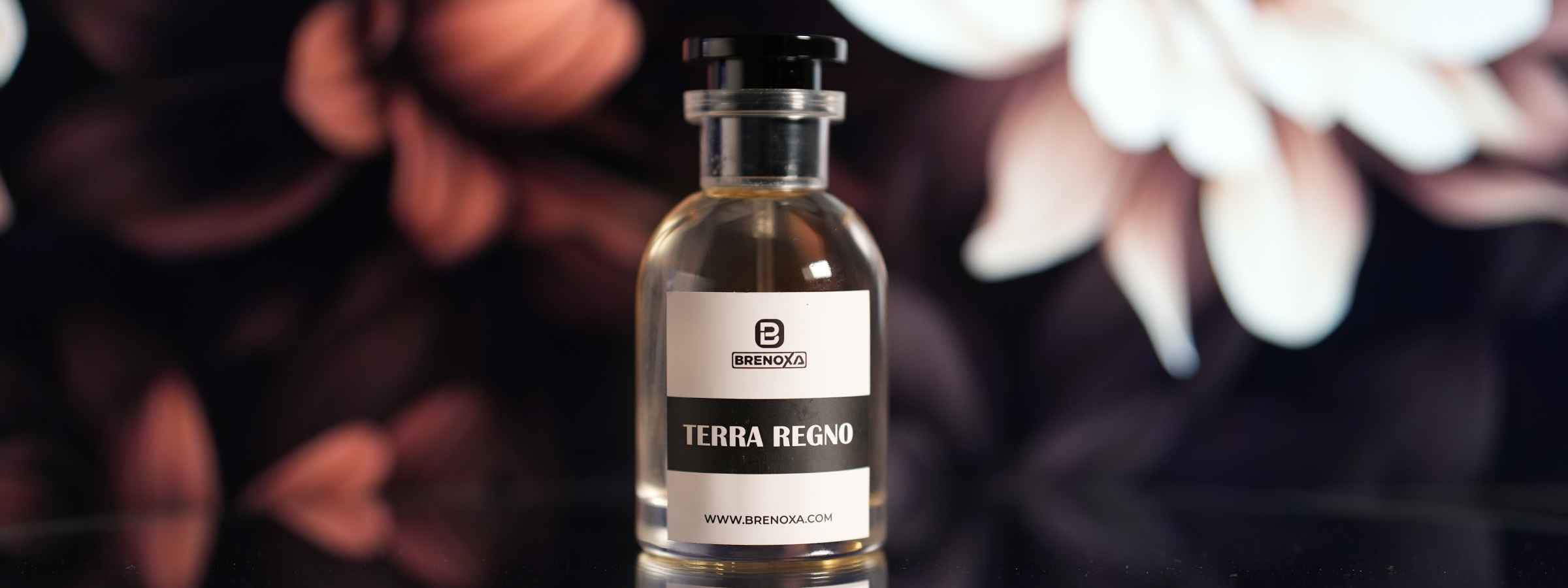 Terra Regno by BRENOXA perfume bottle on reflective surface with soft floral background.