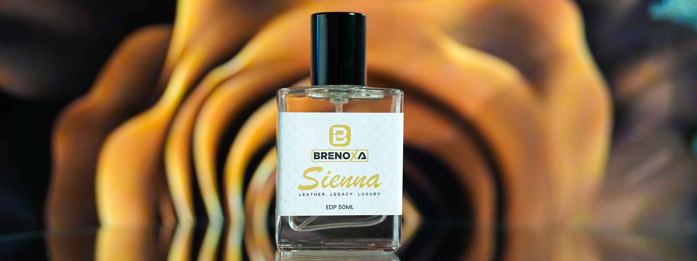 Brenoxa Sienna perfume bottle with leather label on warm brown-gold abstract background.